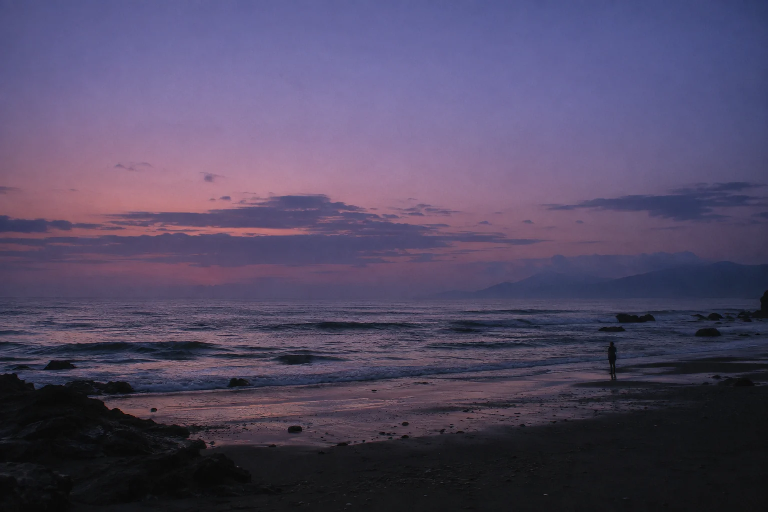 A quiet shoreline at dusk beneath a lavender sky
